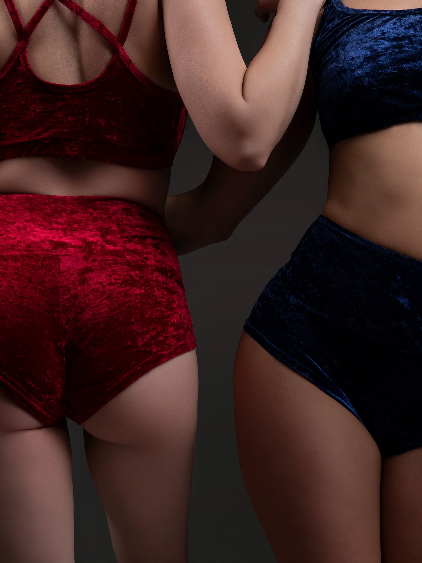 Due donne in set da pole dance, top e short, in velluto blu e rosso, stile lusso