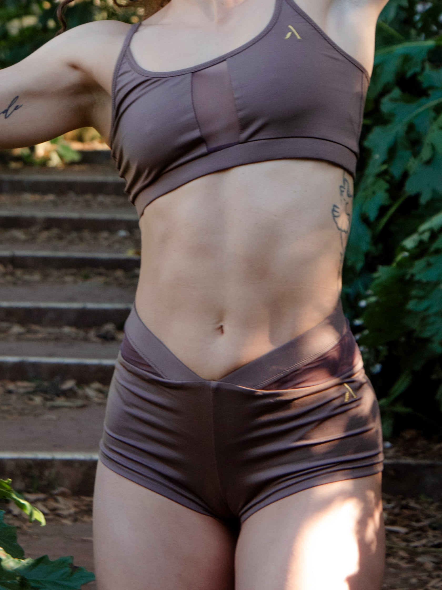 Donna in completo da pole dance marrone, top e pantaloncini, con inserti in rete