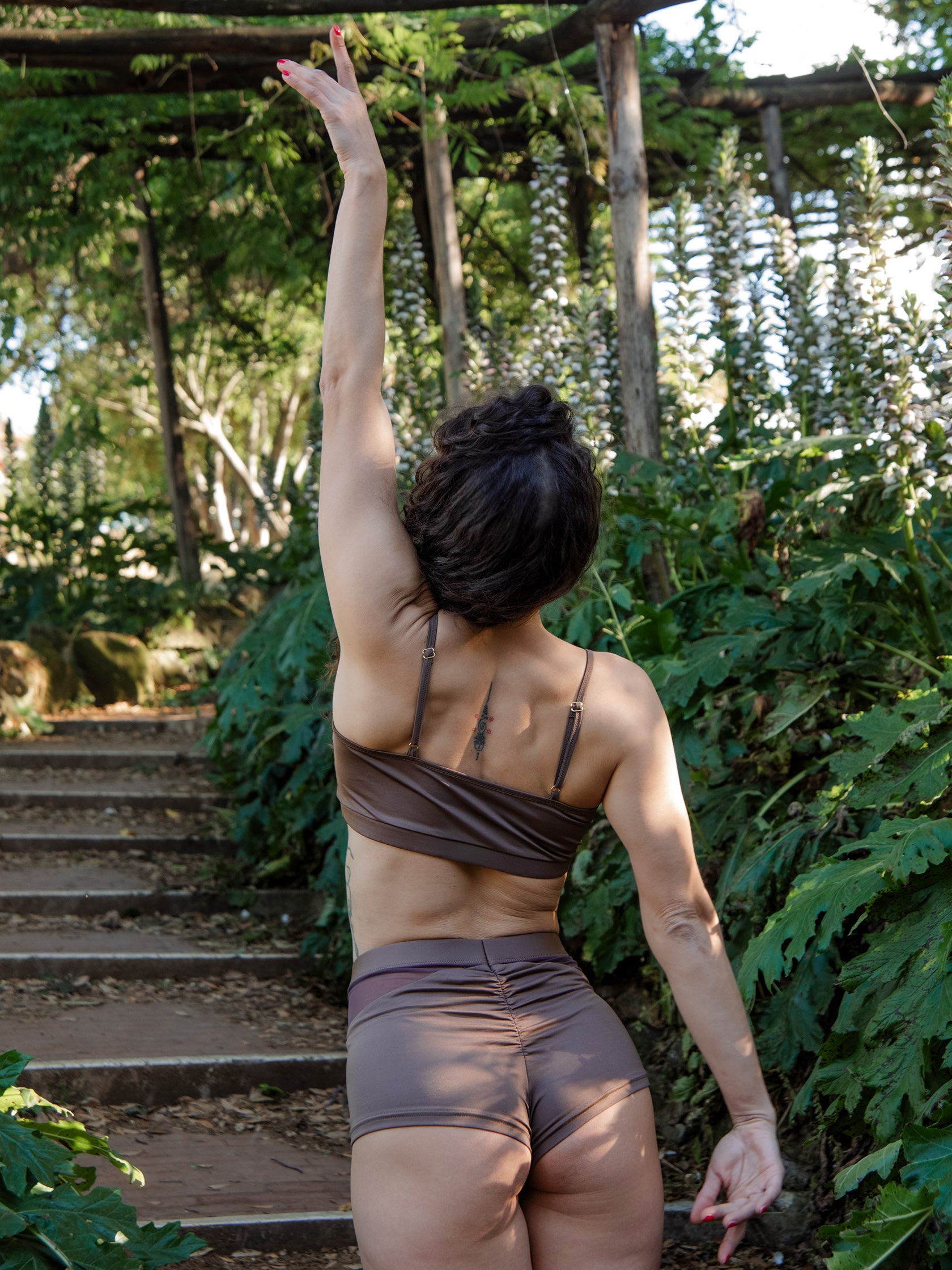 Donna in completo da pole dance marrone, top e pantaloncini, con inserti in rete