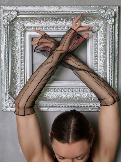 Donna in set da pole dance con top e pantaloncini, indossa manicotti in rete trasparente come accessorio