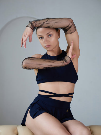 Donna in set da pole dance con top e pantaloncini, indossa manicotti in rete trasparente come accessorio