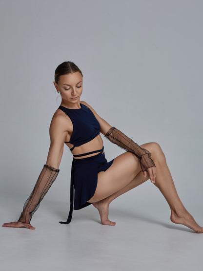 Donna in set da pole dance con top e pantaloncini, indossa manicotti in rete trasparente come accessorio