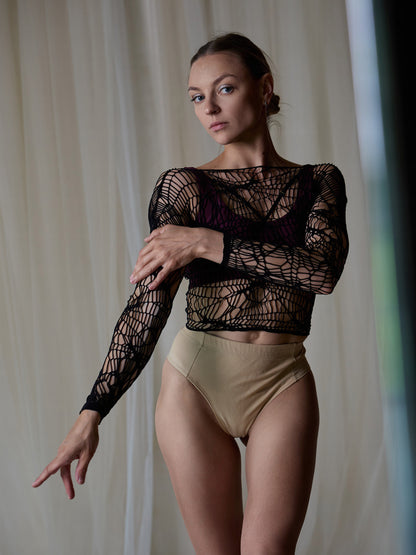 Donna in set da pole dance con top e pantaloncini, indossa una maglia traforata come accessorio