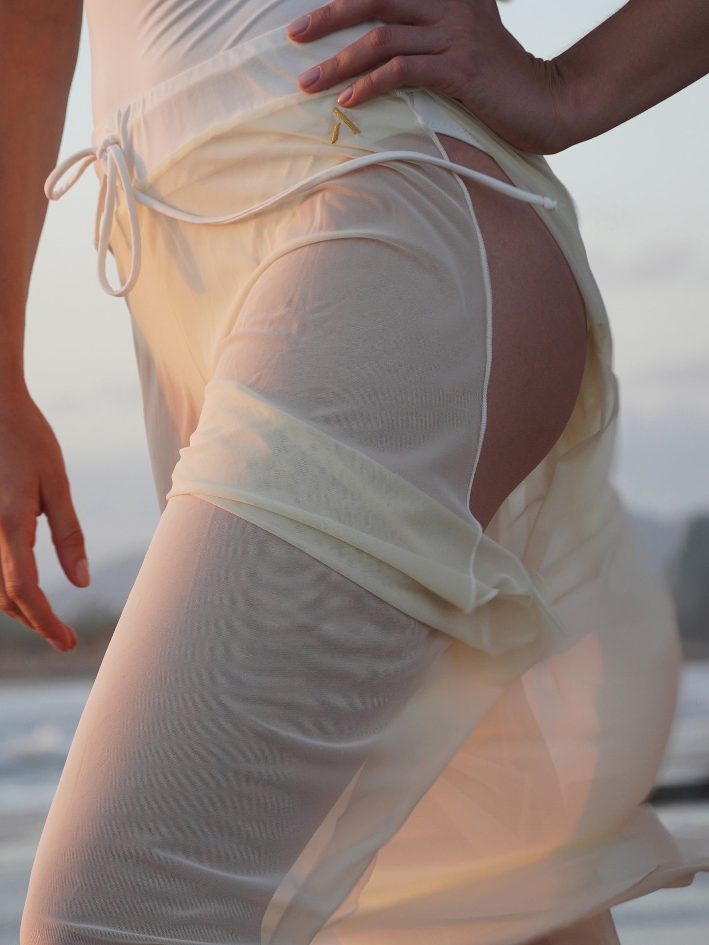 Donna sul palo in completo da pole dance bianco, top a fascia e pantaloni culotte in tulle mesh