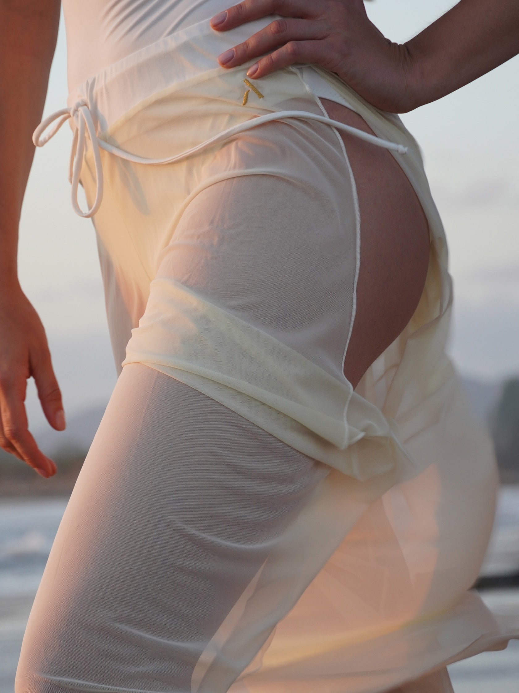 Donna sul palo in completo da pole dance bianco, top a fascia e pantaloni culotte in tulle mesh