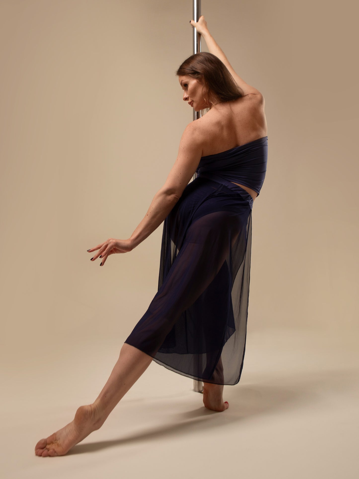 Donna sul palo in completo da pole dance blu, top a fascia e pantaloni culotte in tulle mesh