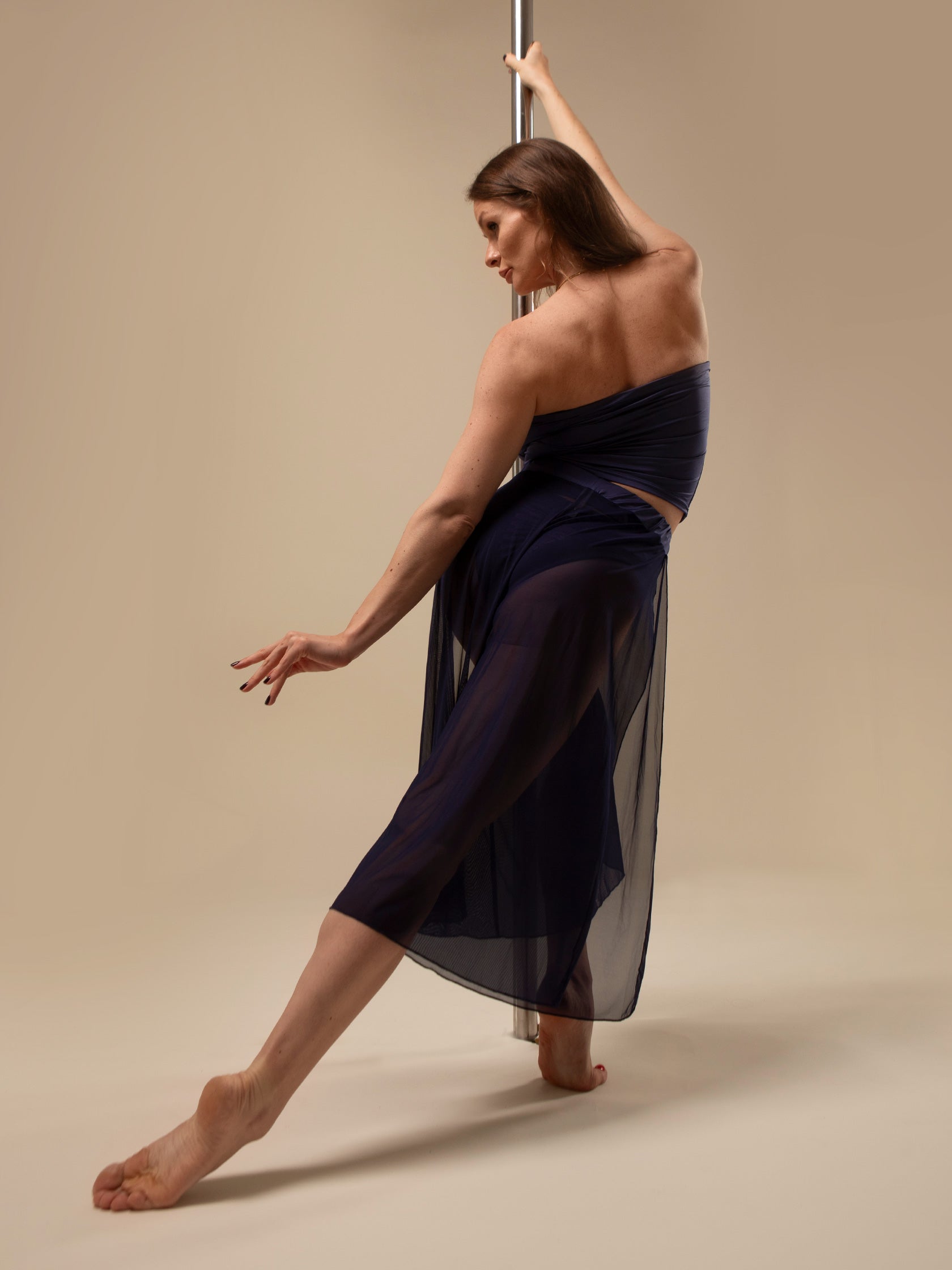 Donna sul palo in completo da pole dance blu, top a fascia e pantaloni culotte in tulle mesh